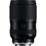 Black Tamron 25-200mm lens standing upright, front three-quarter view, on a white background